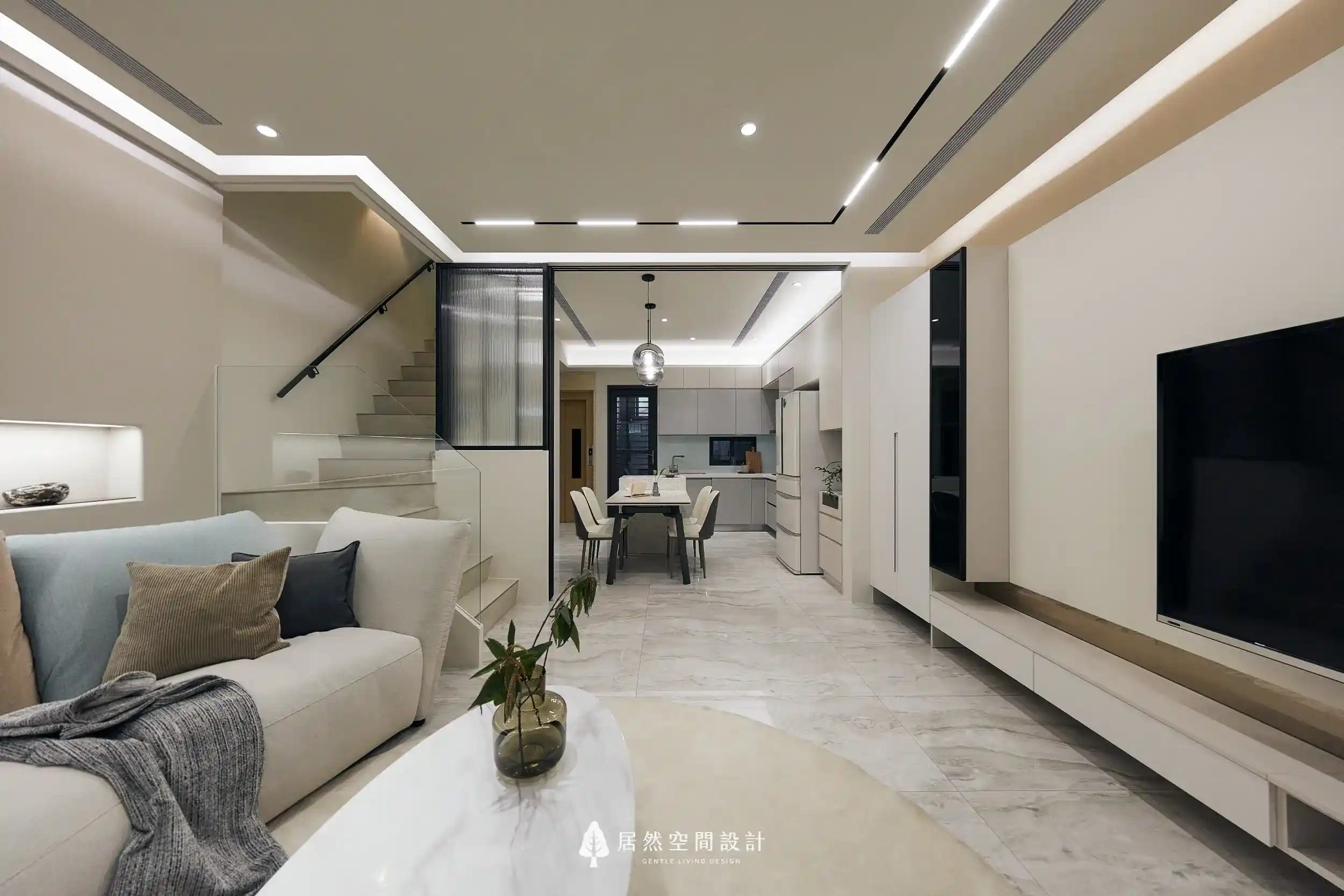 空間專訪-台中雅致光氛透天宅|鋁框玻璃拉門隔出獨立餐廚空間,搭配磁吸式軌道燈,結合淺米色沙發與電視牆設計,呈現溫潤現代的生活場景。