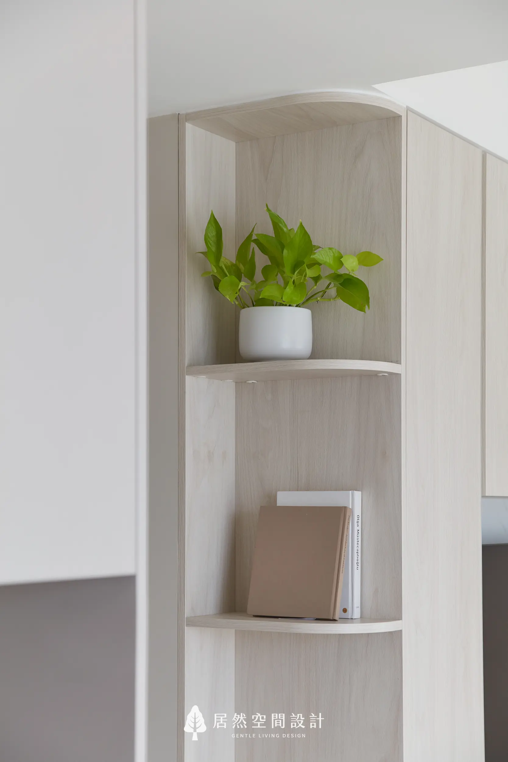 轉角圓弧層板以淺木紋呈現，搭配植栽與書冊陳列，柔化櫃體稜角，增添視覺層次與生活溫度，讓收納成為空間端景細節耐看質感日常