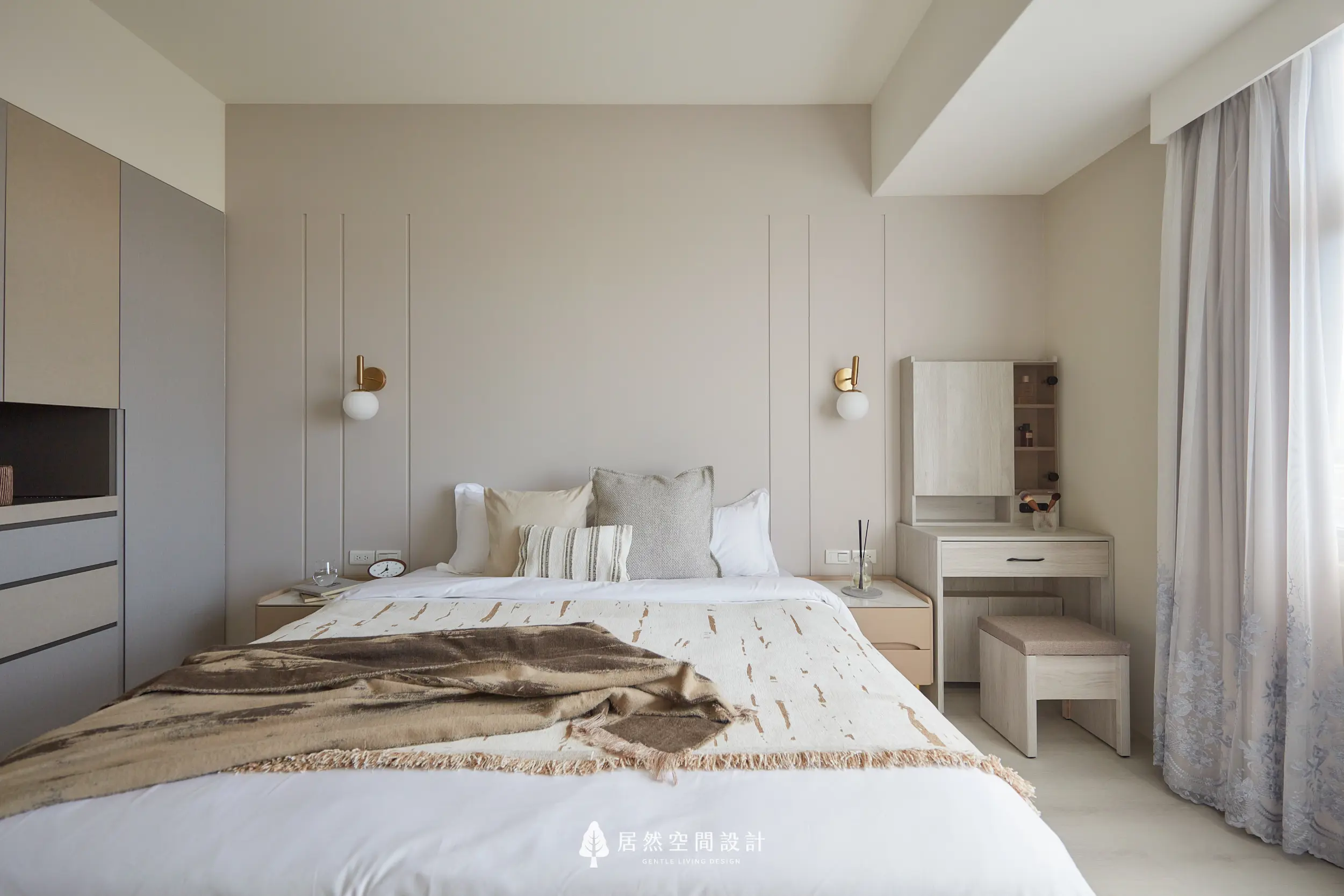 主臥以床頭線板與圓形壁燈營造平衡感，淺色床組搭配梳妝桌與窗邊採光，整體色調柔和安定，形塑舒眠放鬆且機能齊備的私人空間