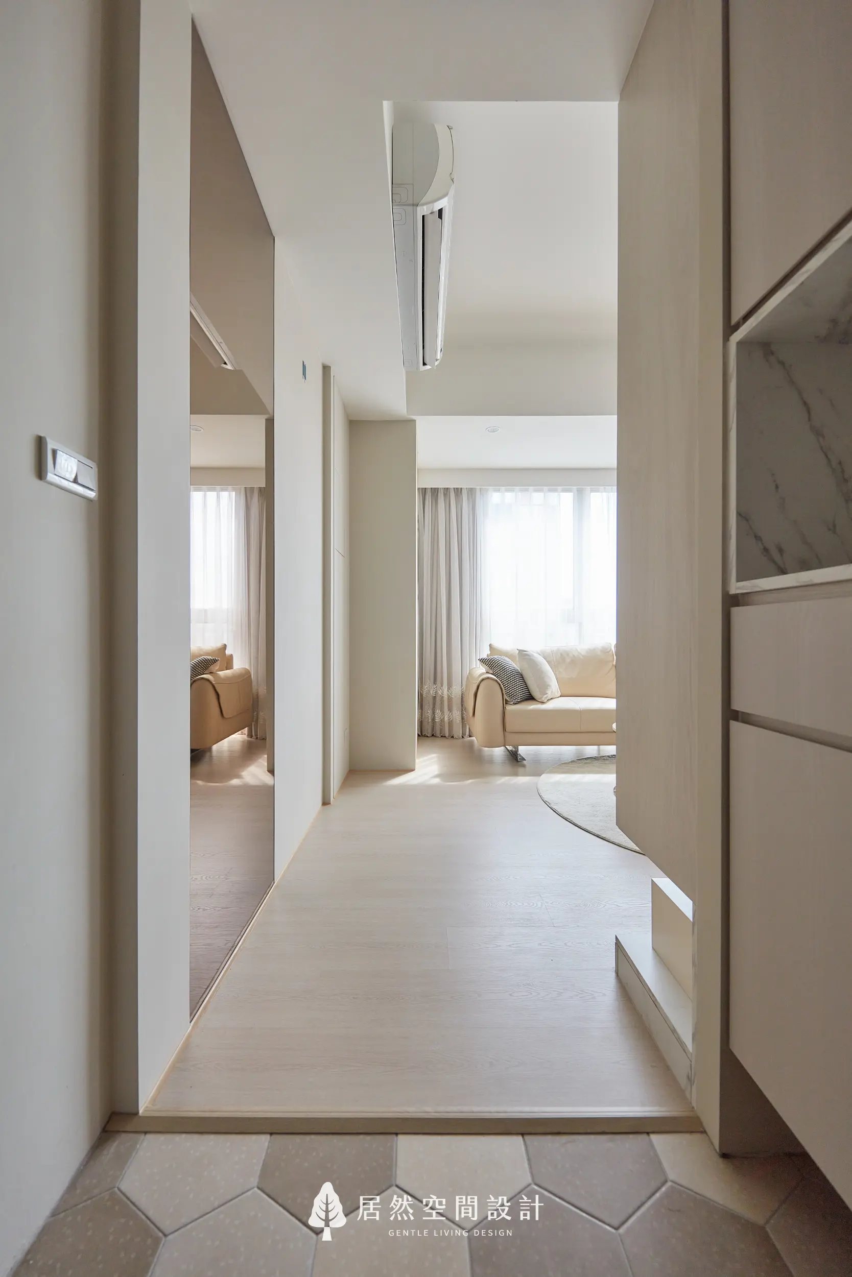 玄關銜接客廳以架高木地坪劃分落塵區，動線筆直通透，隱藏式空調與淺色調牆面延伸空間感，營造明亮柔和的居家過渡場域
