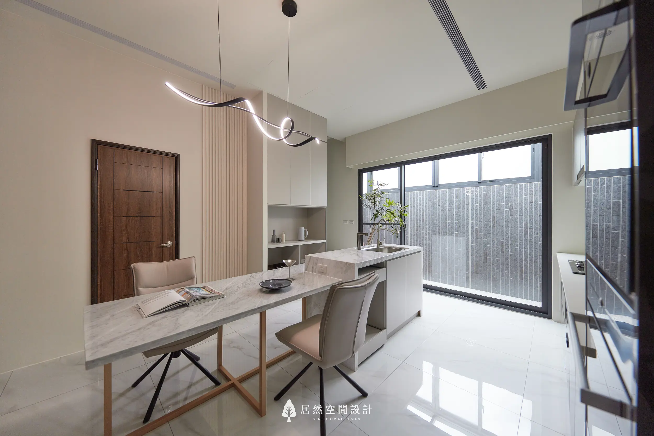 餐廳以大理石紋餐桌結合中島形成料理與用餐動線，搭配造型吊燈與收納櫃體，後方落地窗引入自然採光延伸空間視覺