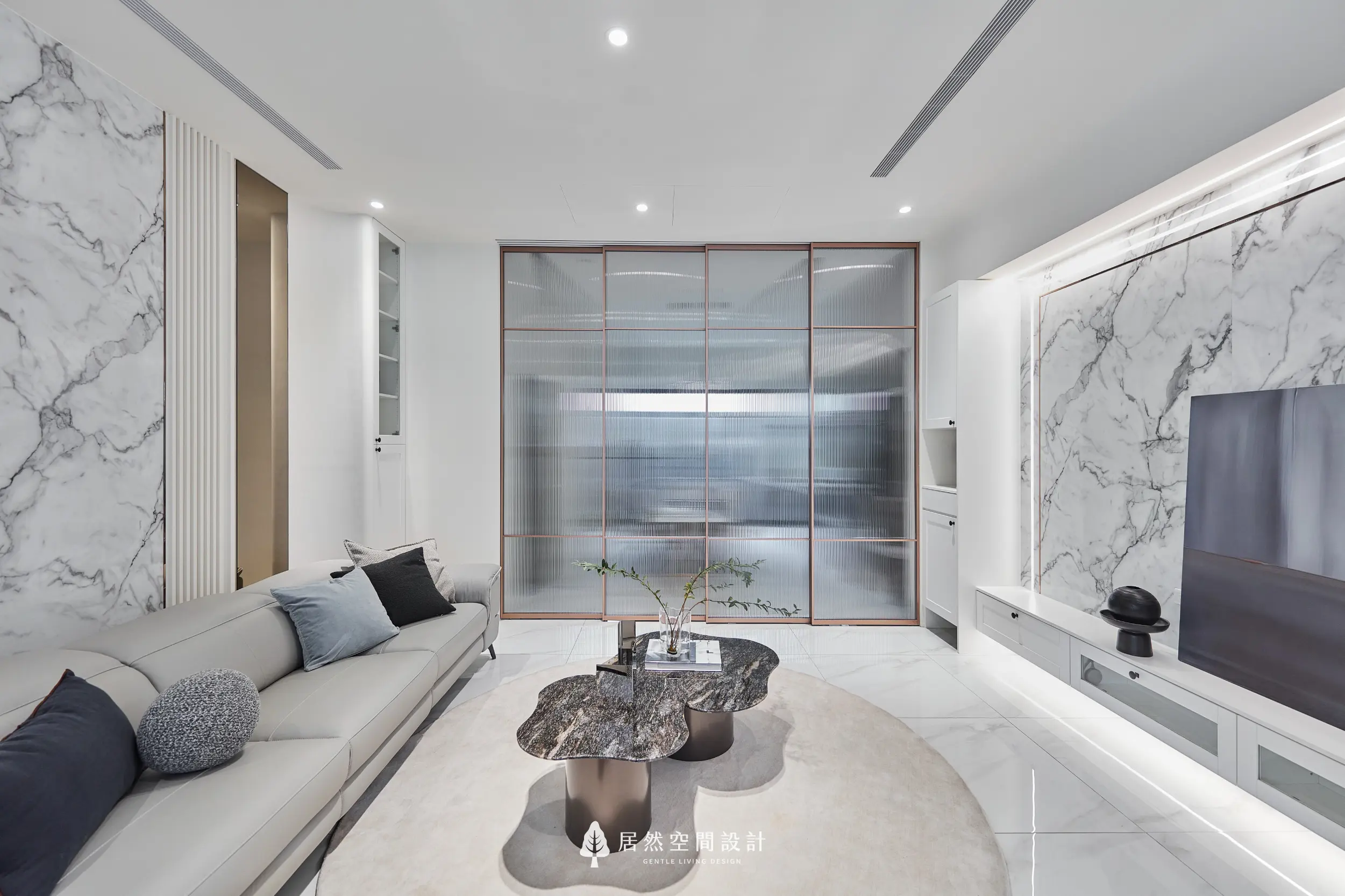 客廳以大理石紋理電視牆與隱藏燈帶形塑空間主軸，米色沙發搭配深色石紋茶几形成層次，長虹玻璃拉門界定餐廳區域並維持通透採光感