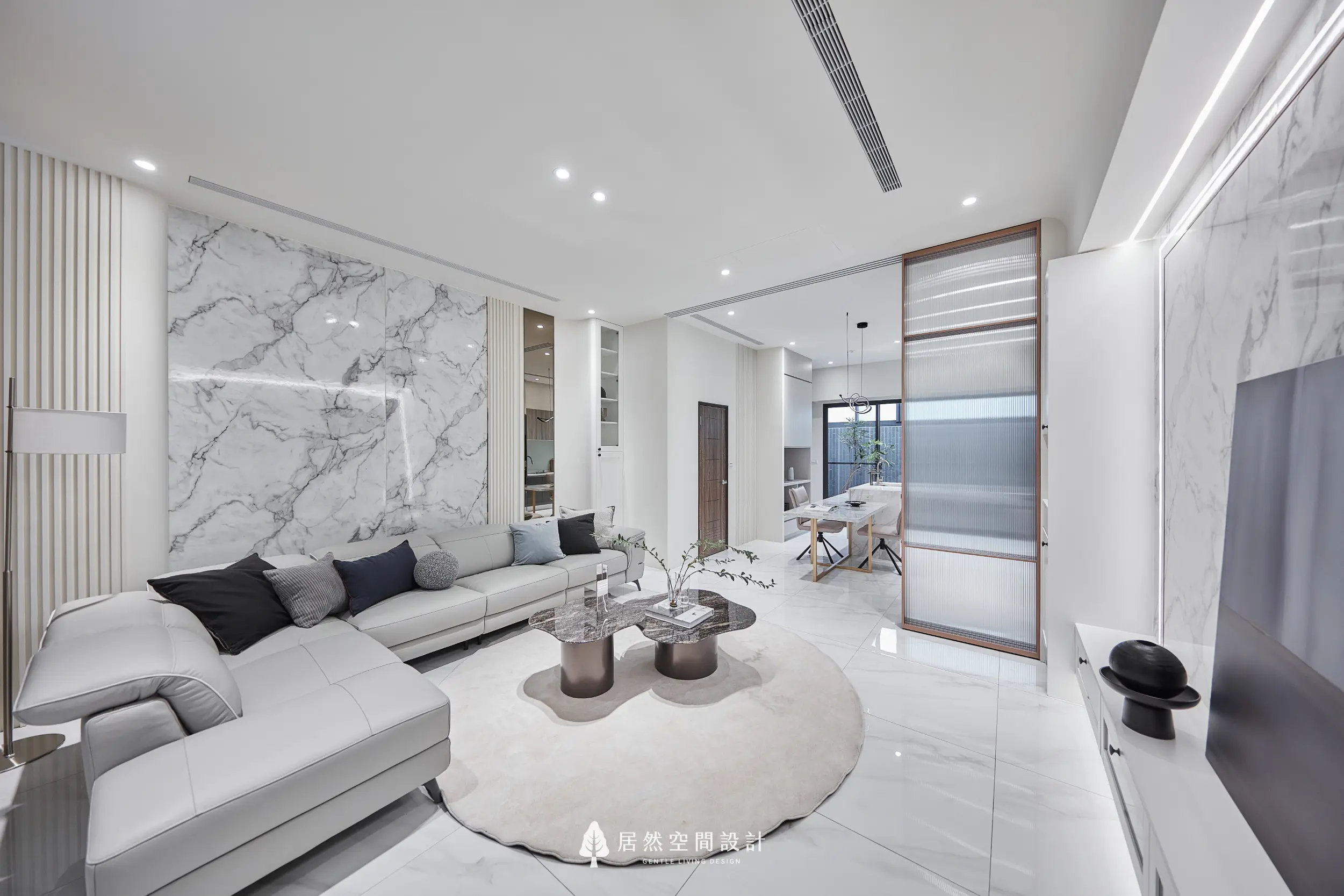客廳以大理石紋理電視牆鋪陳主要視覺，搭配米色L型沙發與深色石紋茶几形成層次，長虹玻璃拉門串聯餐廳空間