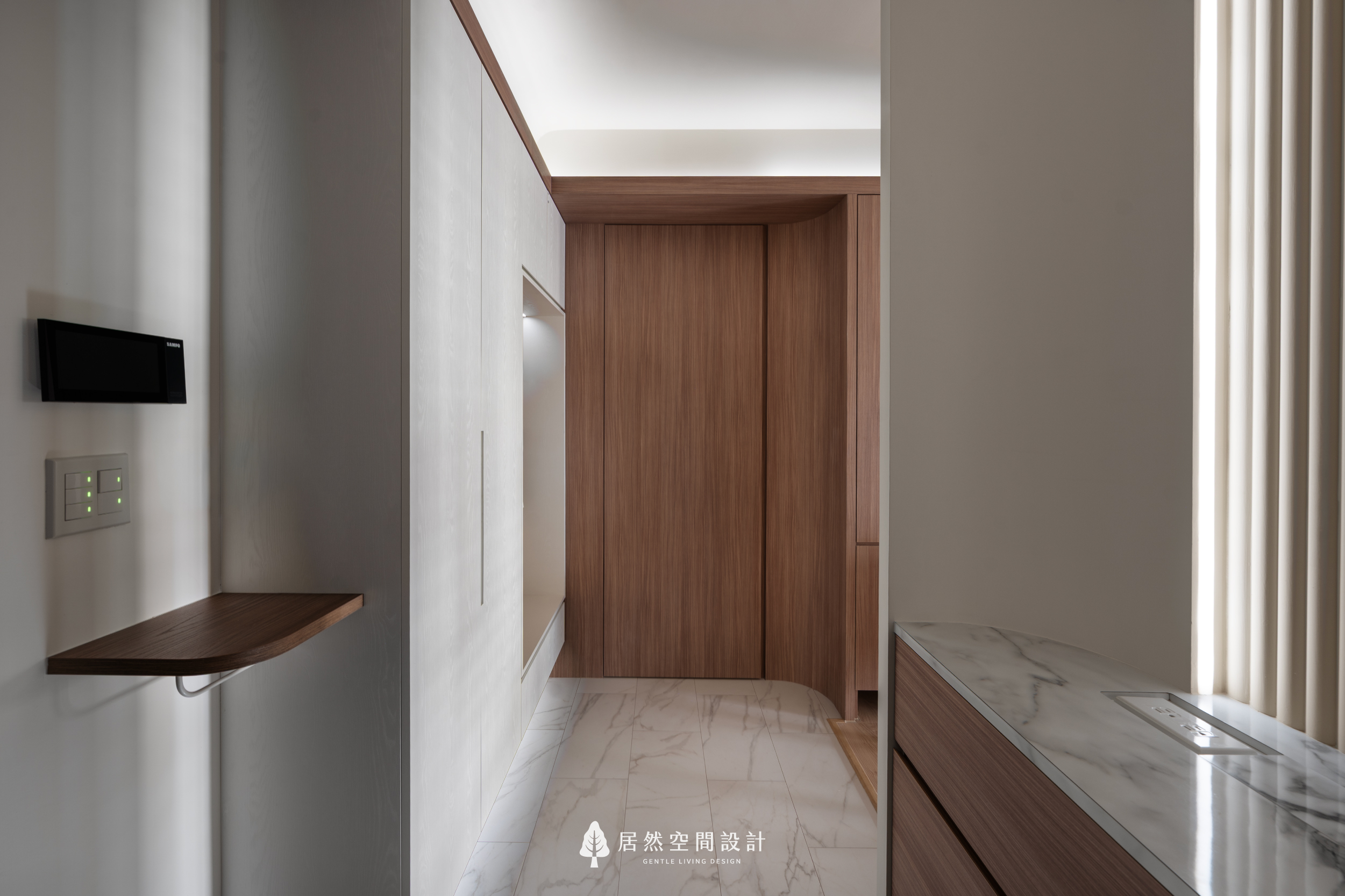 現代風室內設計玄關實景，居然空間設計運用大理石紋地坪搭配淺木色收納櫃，轉角處以圓弧木質立面引導視覺動線，展現簡約優雅的新成屋落塵區美學。