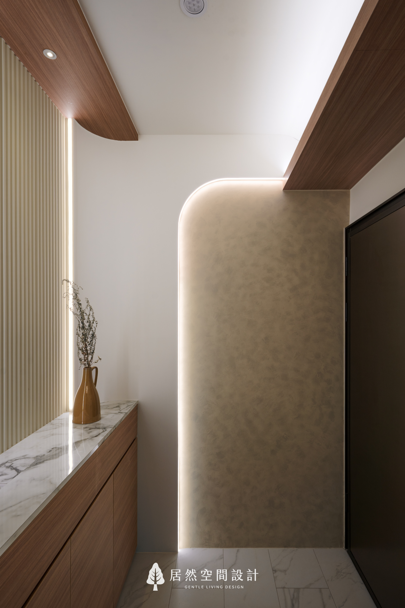現代風室內設計玄關細節，在藝術塗料牆面鑲嵌圓弧燈帶，結合木質天花與大理石平台，透過柔和光影交織，展現24坪新成屋優雅且具層次感的入室端景。