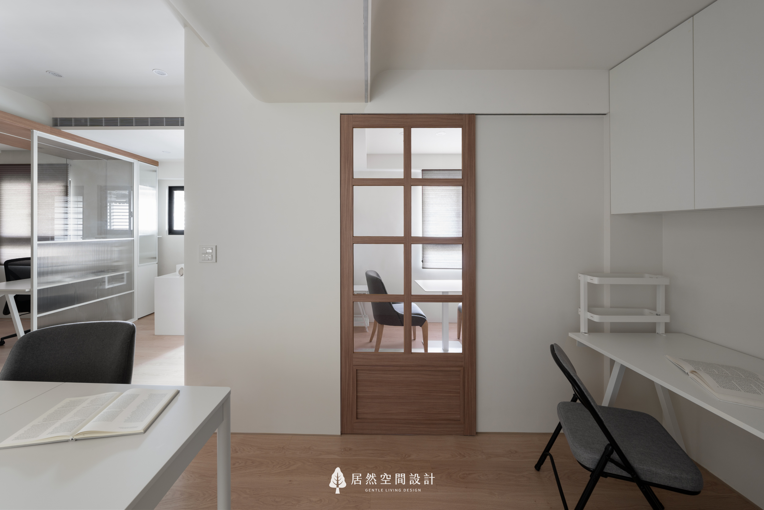現代風會議空間，採用木質邊框玻璃滑門，保持視線通透並靈活劃分場域。透過純白牆面與木地板鋪陳，營造出寧靜且具備隱私感的居家辦公與閱讀環境。