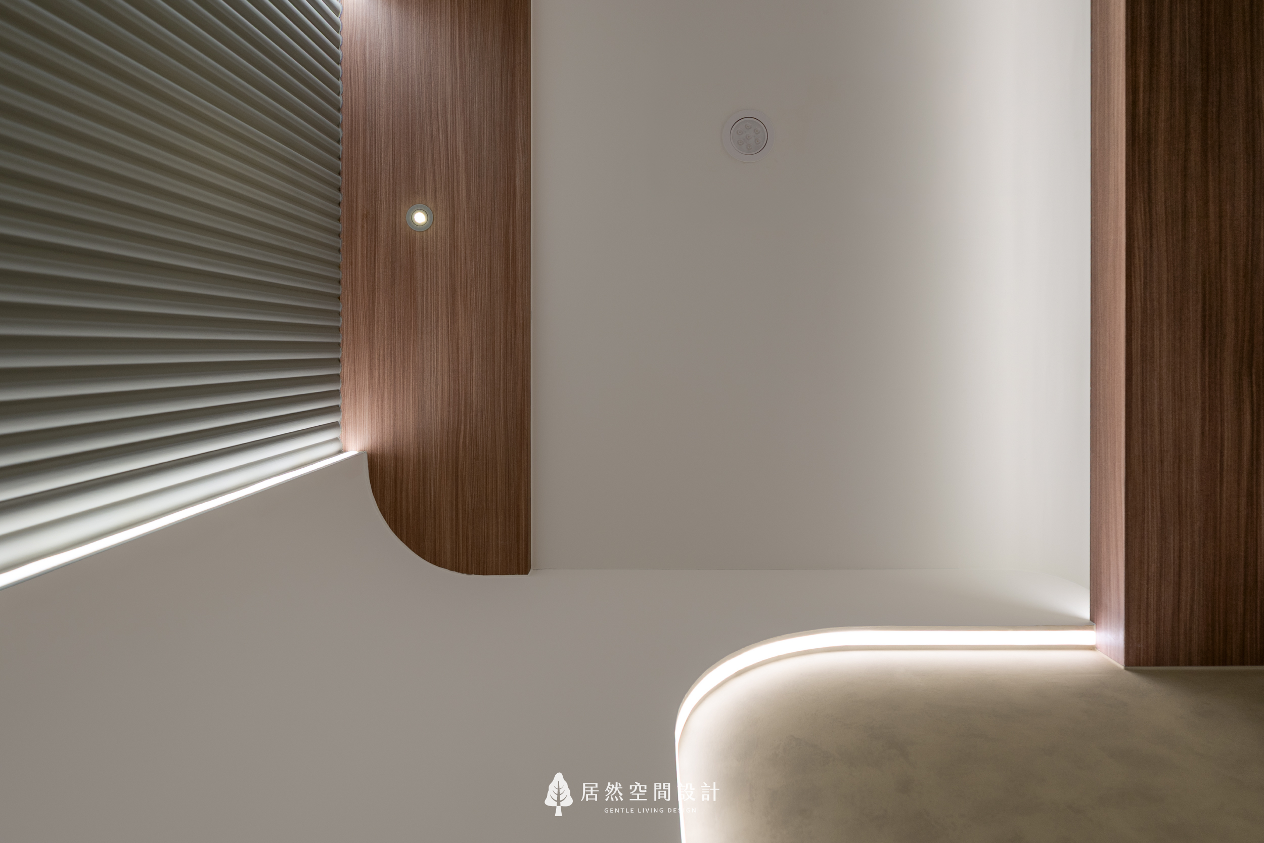 現代風室內設計天花細節，居然空間設計結合胡桃木質與圓弧造型燈帶，透過流暢線條與間接照明，為新成屋玄關營造溫潤且細膩的入室氛圍。