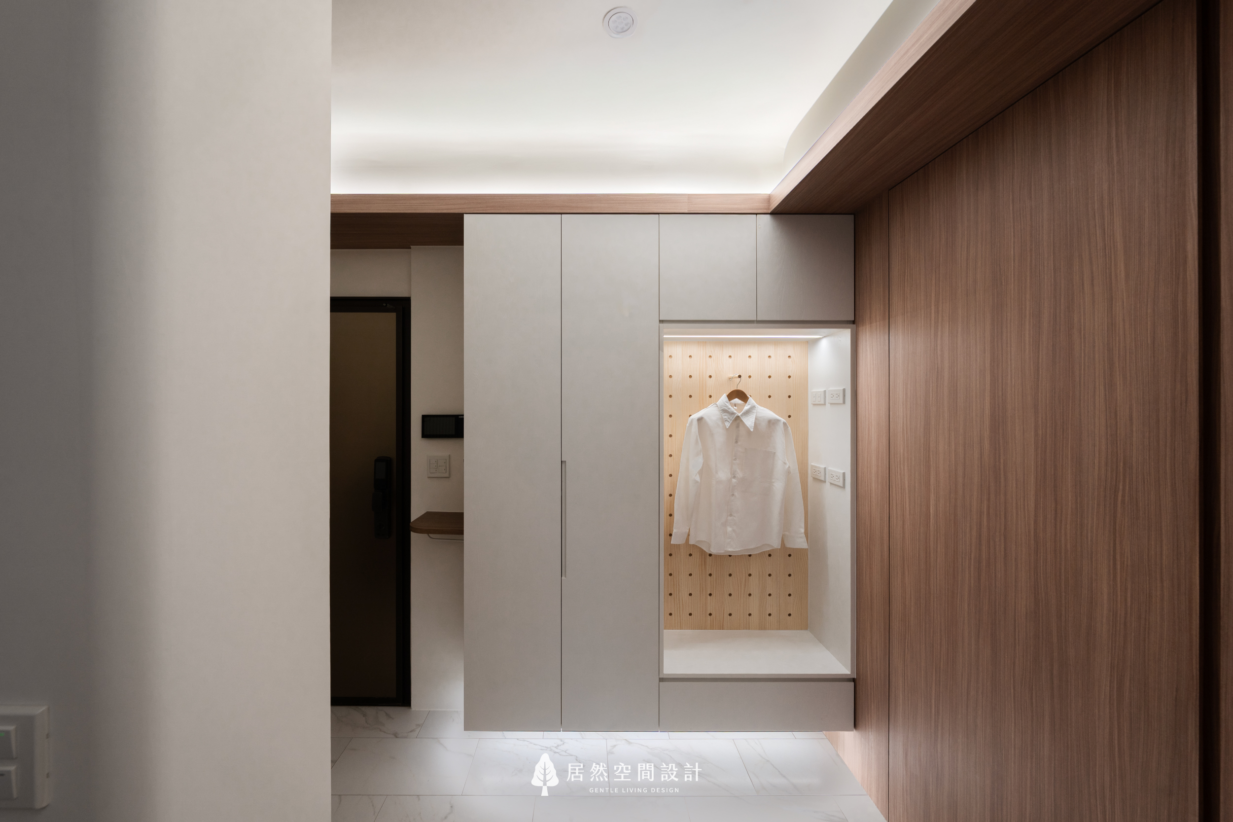 現代風室內設計大門旁機能櫃，利用懸空櫃與洞洞板增加收納彈性，結合間接照明與木質元素，為新成屋打造精緻的門旁掛衣區與鞋櫃收納空間。