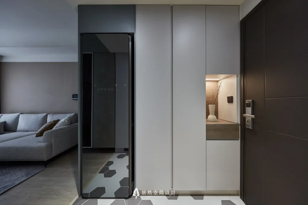 科技健康宅玄關設計案例。居然空間設計利用原格局的樑下空間，完美嵌入電子衣櫥與現代風系統鞋櫃，深淺異材質層次分明，讓玄關成為守護家人的第一道科技防護防線。