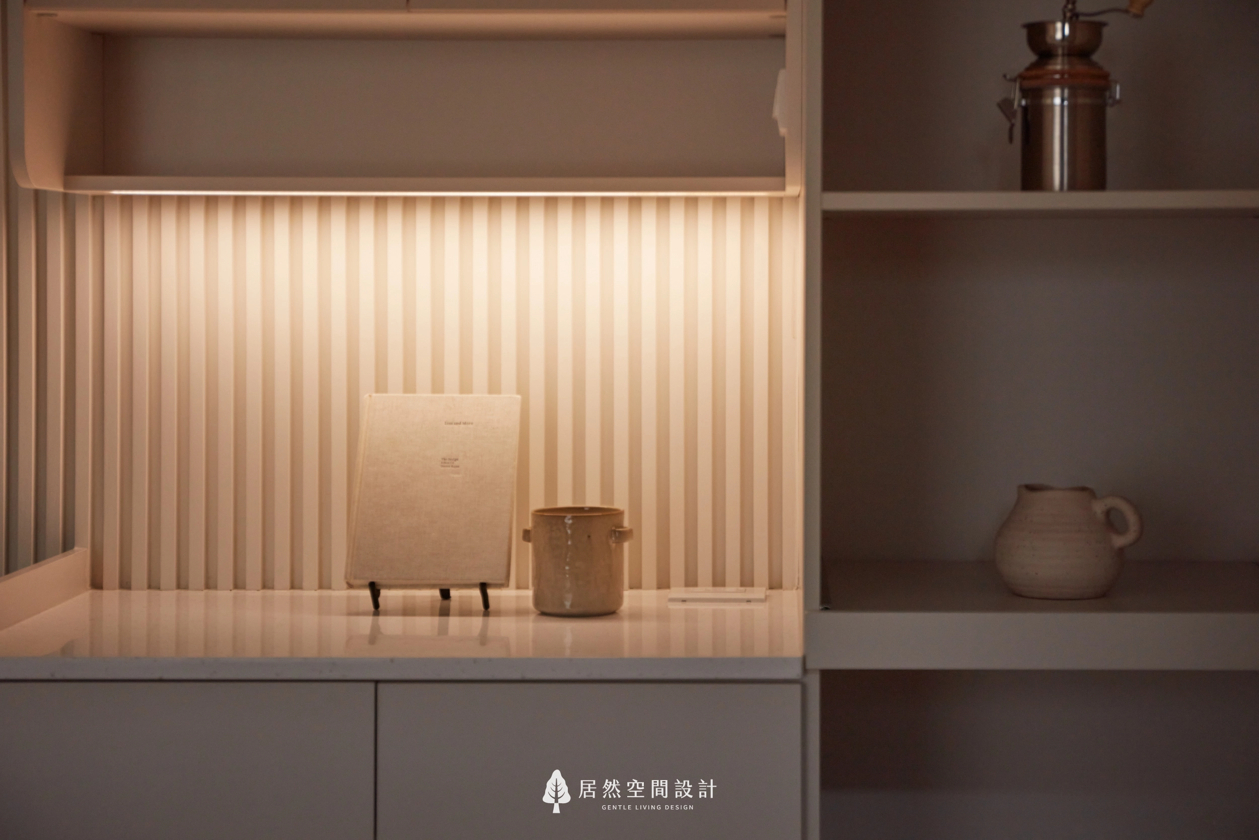 台中13坪北歐風新成屋餐邊櫃細節,以格柵造型背板搭配暖色間接照明、奶茶色櫃體與開放展示層架,透過簡約器皿與擺飾點綴,展現溫潤細膩且富有生活感的居家氛圍。